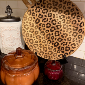 Round wood cutting board laser-engraved with a leopard print pattern, displayed on a kitchen counter