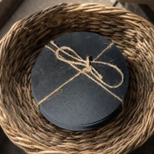 Stack of round slate coasters tied with twine in a woven basket