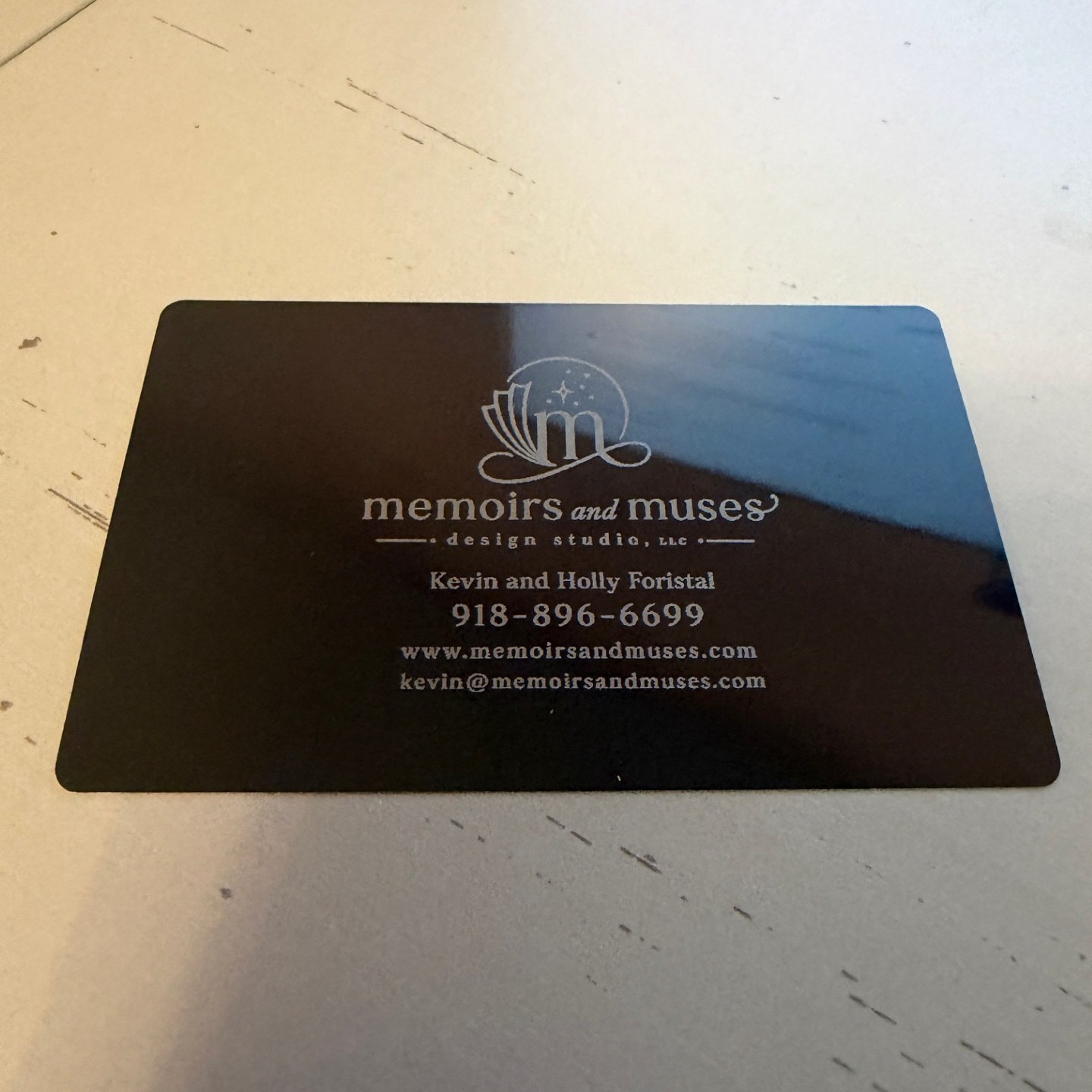 Black aluminum business card laser-engraved with a logo, names and contact details